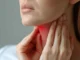 A person holds their hands to their throat and neck, highlighted with a red glow to indicate pain or a sore throat, representing Throat Conditions in North Logan, UT.