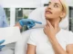 Blonde woman touches her neck as a person in scrubs points during a Speech & Swallowing Disorders consultation in North Logan, UT.